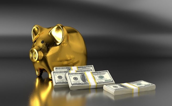 Image of money stacked next to a gold piggy bank to symbolize the money saved using a DSCR loan.